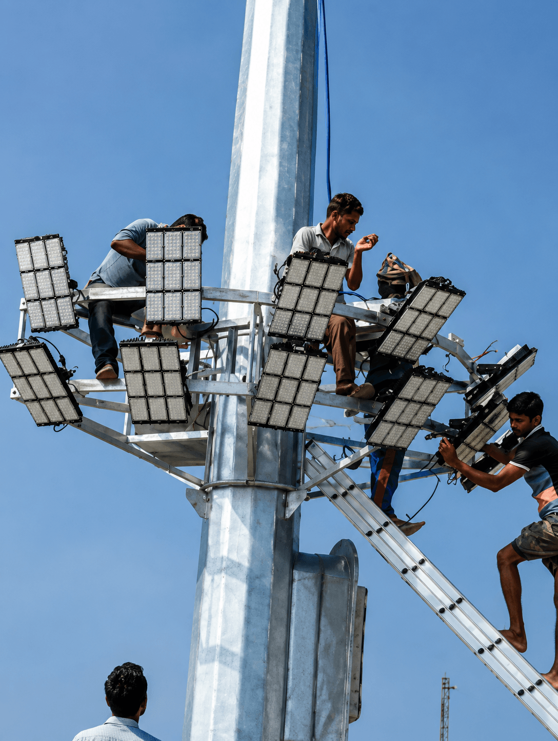 Technicians fitting flood light arrays to a high-mast pole at Payra Port