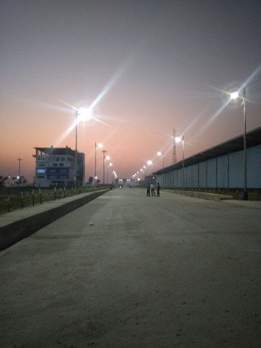 Street lighting columns lit at dusk along a newly built road at Payra Port