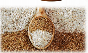 White, brown and red rice varieties arranged around a wooden spoon